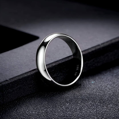 Alliance classique de mariage en acier inoxydable posée sur un rebord noir.