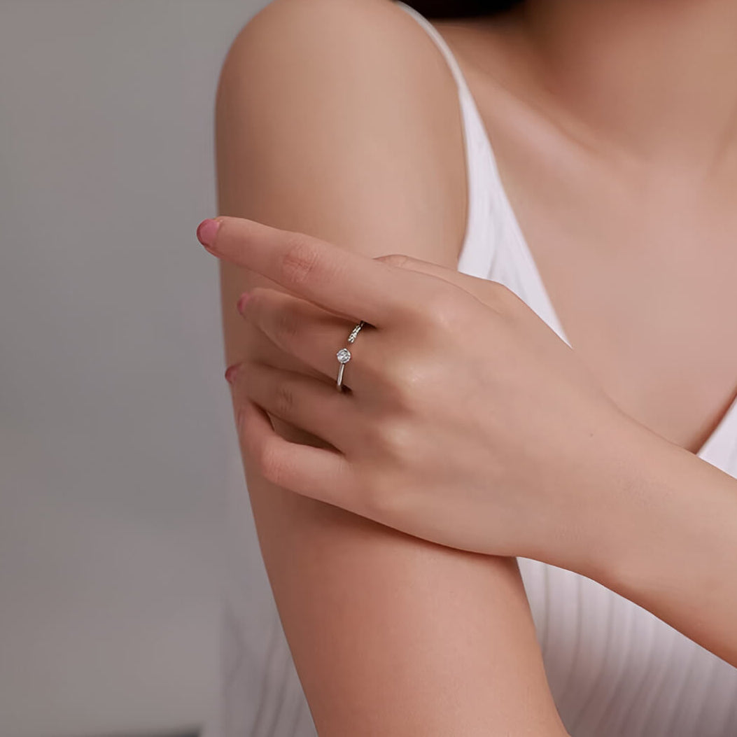Alliance de mariage ouverte halomira en argent 925 plaqué or blanc et diamants étincelants portée au doigt d'une femme vue de loin.