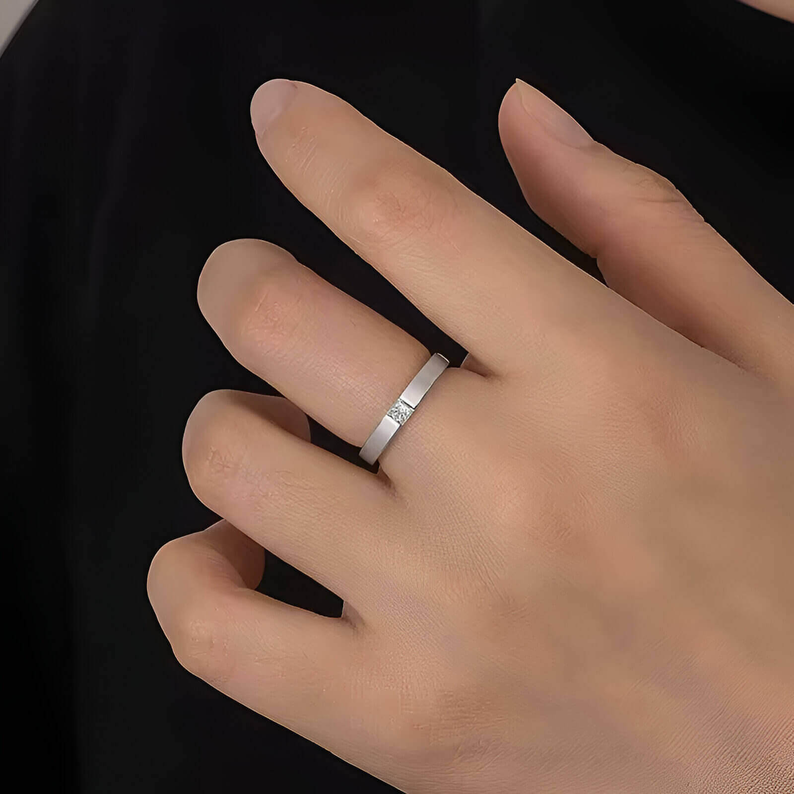 Alliance diamant princesse serti clos Andréa en argent 925 plaqué or blanc portée au doigt d'une femme vue de proche.