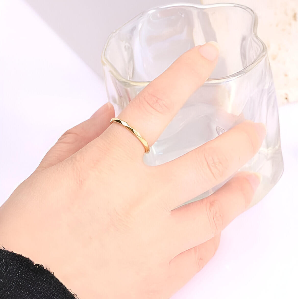 Alliance discrète multi-facettes dorées Noa en acier plaqué or jaune 14K chaleureux portée au doigt d'une femme.