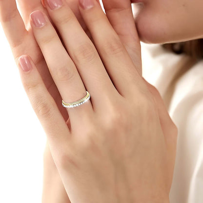 Alliance duo fine en or jaune et en or blanc sertie de diamants synthétiques portée au doigt d'une femme.