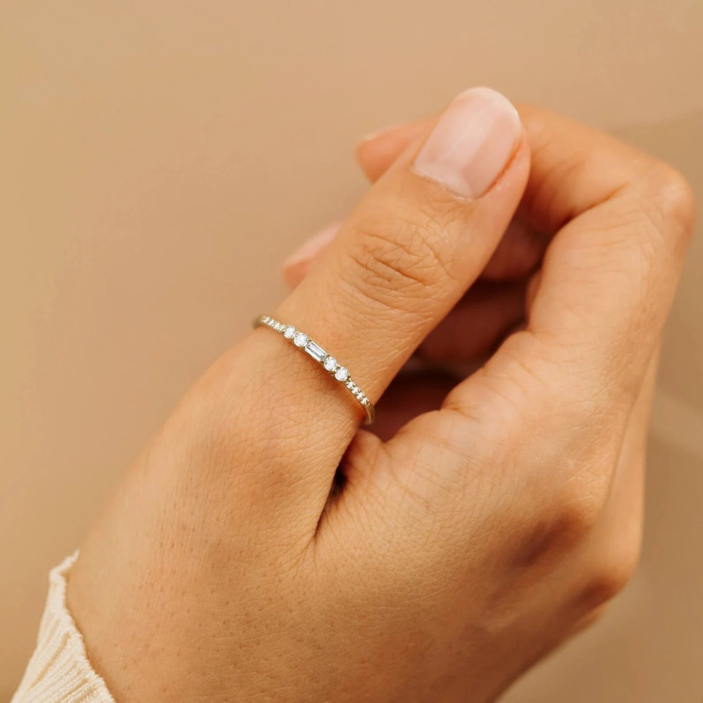 Alliance en or jaune et oxyde de zirconium portée au doigt d'une femme vue rapprochée.