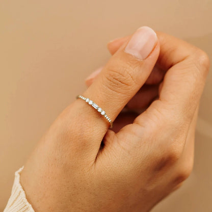 Alliance en or jaune et oxyde de zirconium portée au doigt d'une femme vue rapprochée.