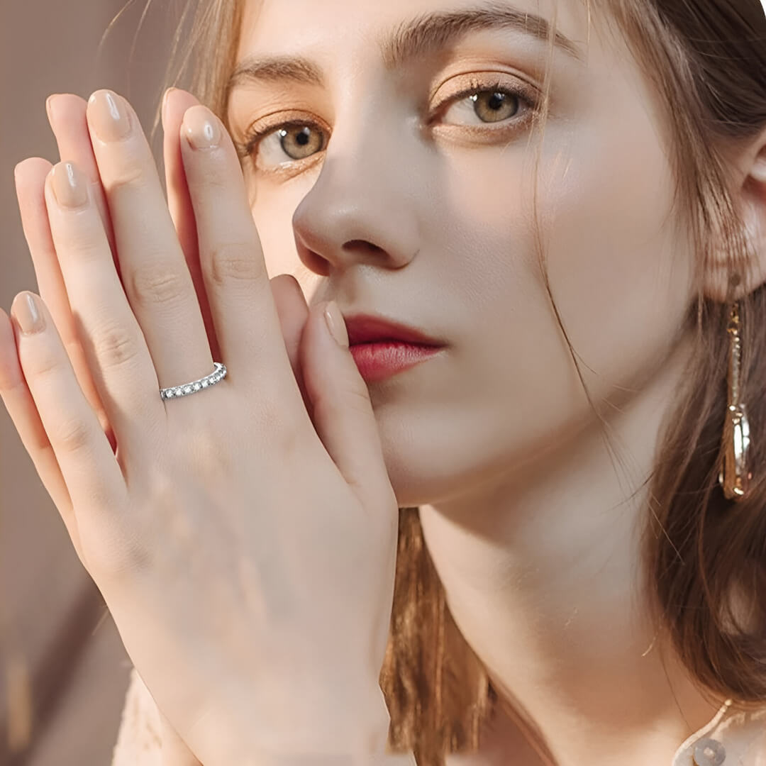 Alliance éternité épaisse 3mm Samira en argent 925 plaqué or blanc discret et diamants portée au doigt d'une femme vue de face.