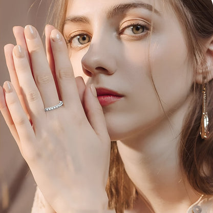 Alliance éternité en or blanc et diamants synthétiques portée au doigt d'une femme.