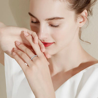 Alliance éternité en or blanc et diamants synthétiques portée au doigt d'une femme vue de loin.