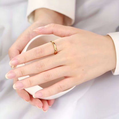 Alliance facettée de 4mm en tungstène et or jaune portée au doigt d'une femme vue de loin.