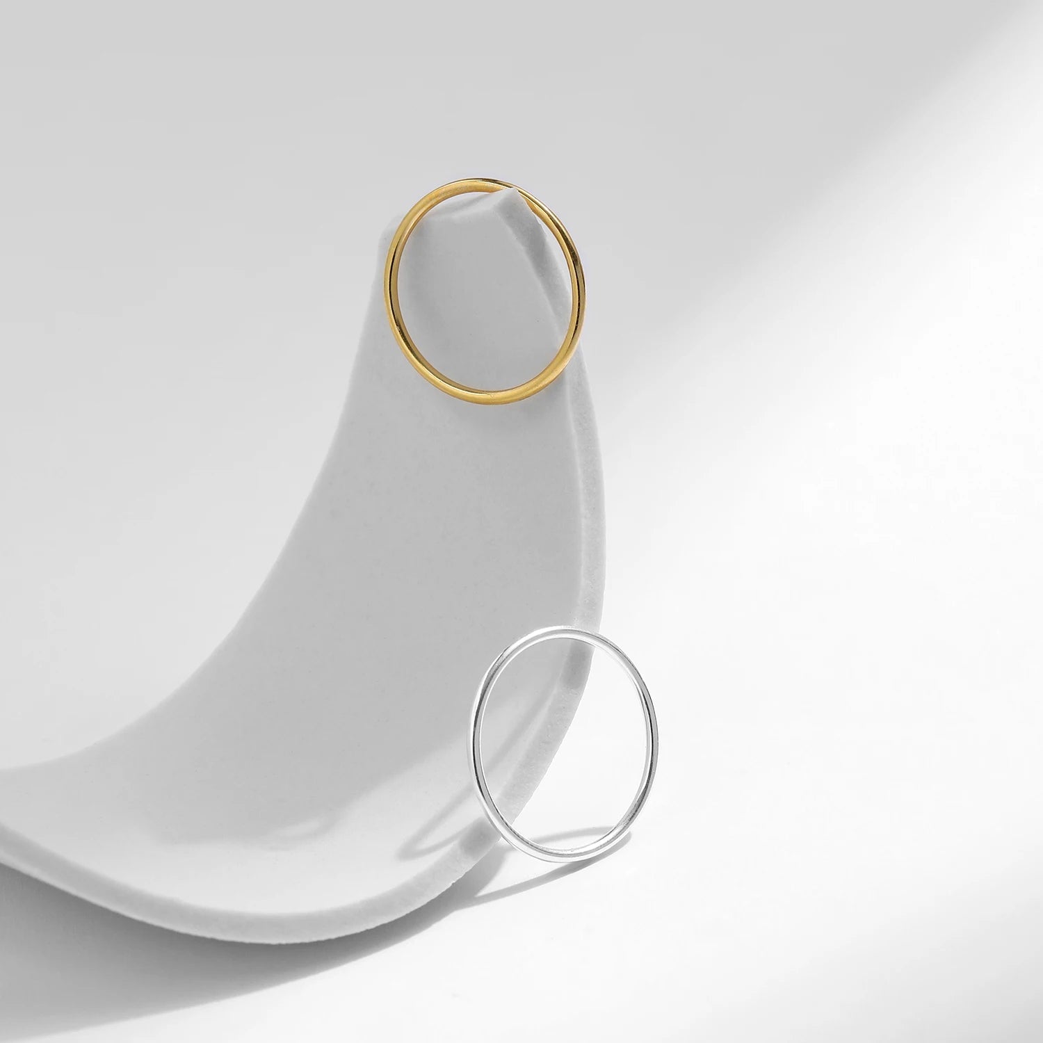 Variantes de l'alliance fine classique Lyandra en argent 925 plaqué or jaune lumineux ou plaqué or blanc discret posées sur un socle blanc.