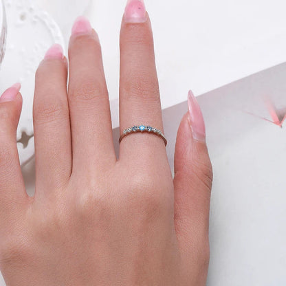 Alliance fine diamant bleu Perlina en argent 925 plaqué or blanc portée au doigt d'une femme.