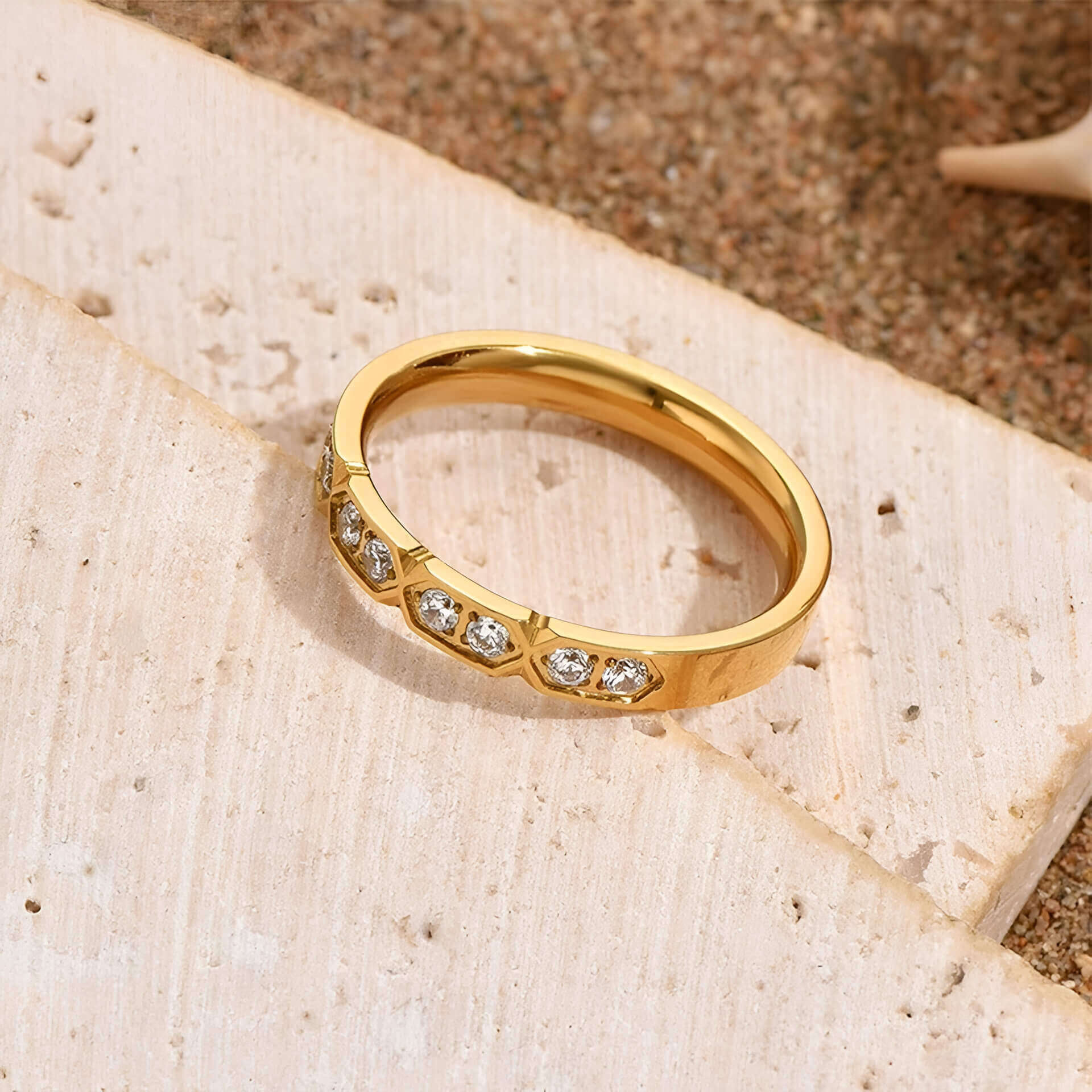 Alliance gravée alvéolée en acier inoxydable et or jaune sertie de cristaux posée.