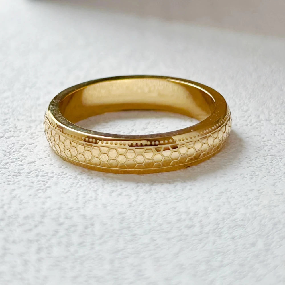 Alliance gravée motif alvéolé Oréline en acier 316L plaqué or jaune 18K à plat vue de proche.