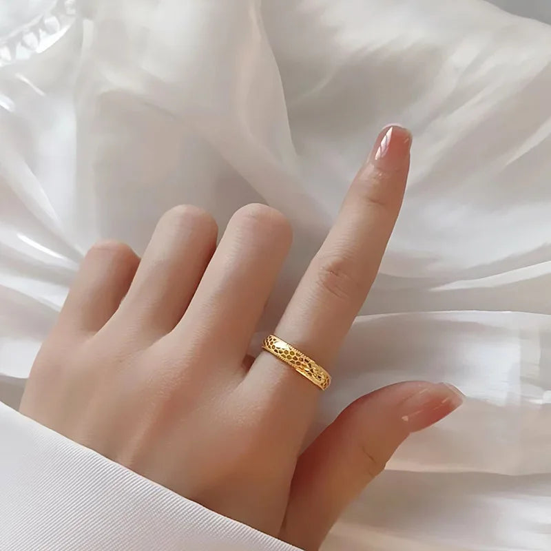 Alliance gravée motif alvéolé Oréline en acier inoxydable 316L plaqué or jaune 18K étincelant portée au doigt d'une femme vue du dessus vue du dessus.