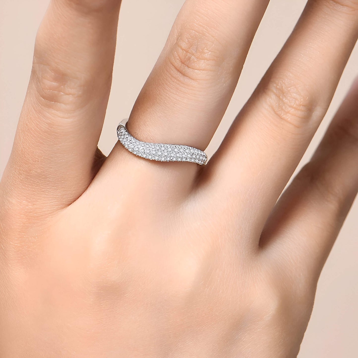Alliance incurvée pavée de diamants éclatants en argent 925 plaqué or blanc portée au doigt d'une femme vue de proche.