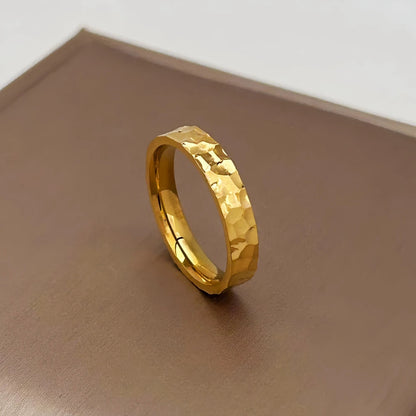 Alliance martelée style unique Lumeris en acier 316L plaqué or jaune 18K debout sur un écrin.