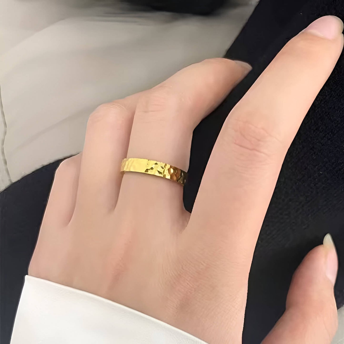 Alliance martelée style unique Lumeris en acier plaqué or jaune 18K portée au doigt d'une femme vue de face.