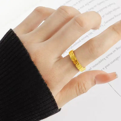 Alliance martelée style unique Lumeris en acier inoxydable plaqué or jaune 18K portée au doigt d'une femme vue du dessus.