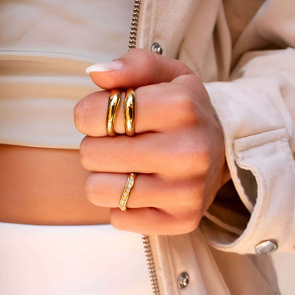 Alliance ondulée en acier et or jaune sertie de diamants naturels portée au doigt d'une femme.