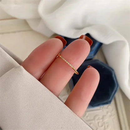 Femme montrant une alliance fine Petites Gemmes en or jaune variante huit pierres vue de dessus.