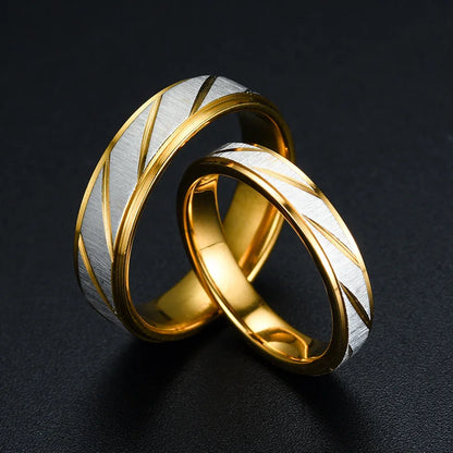 Alliance Couple en acier doré variantes 6mm pour homme et 4mm pour femme entrecroisées sur fond noir.