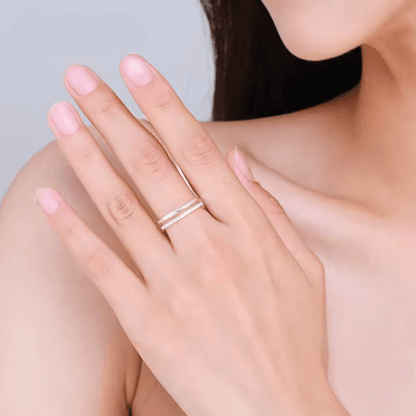 Alliance ouverte ruban de Möbius Alizée en argent 925 plaqué or blanc et diamants éclatants portée au doigt d'une femme vue de face.