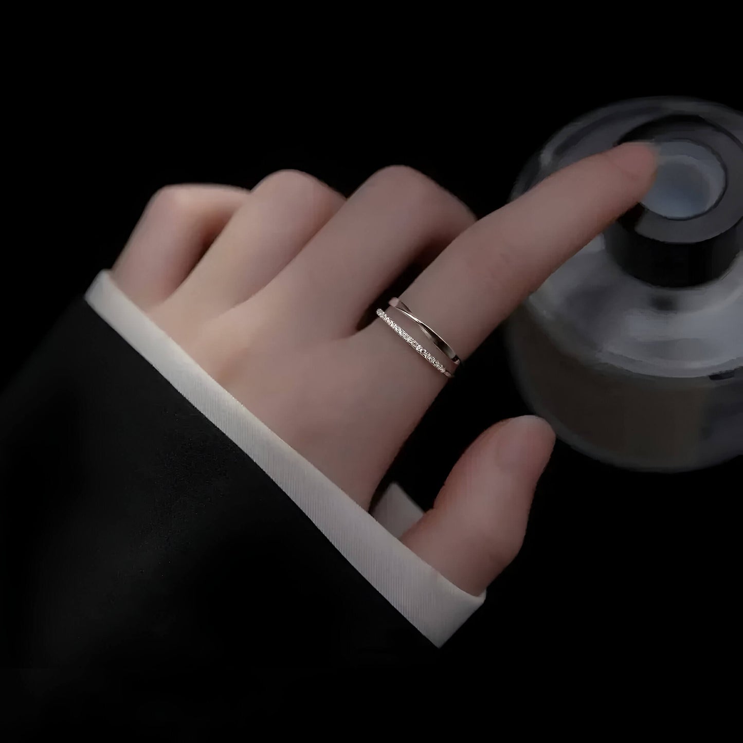 Alliance ouverte ruban de Möbius Alizée en argent 925 plaqué or blanc et diamants portée au doigt d'une femme vue du dessus.