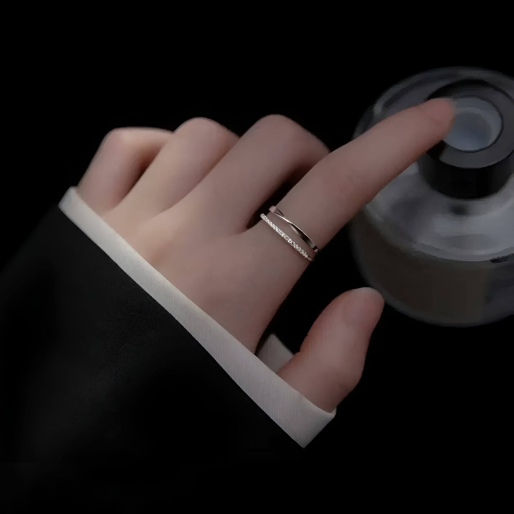 Alliance ouverte ruban de Möbius Alizée en argent 925 plaqué or blanc et diamants portée au doigt d'une femme vue du dessus.