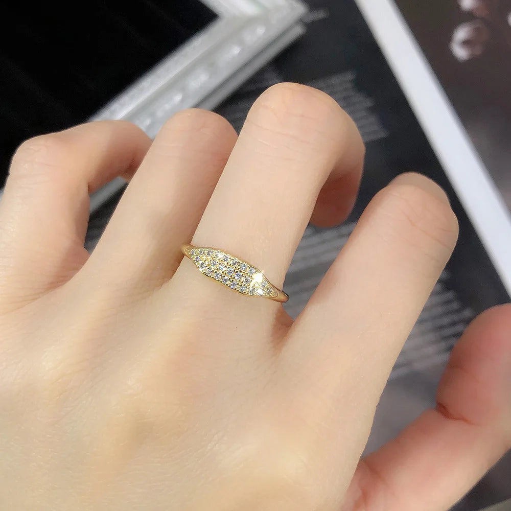 Alliance pavé en or jaune et oxydes de zirconium portée au doigt d'une femme vue de proche.