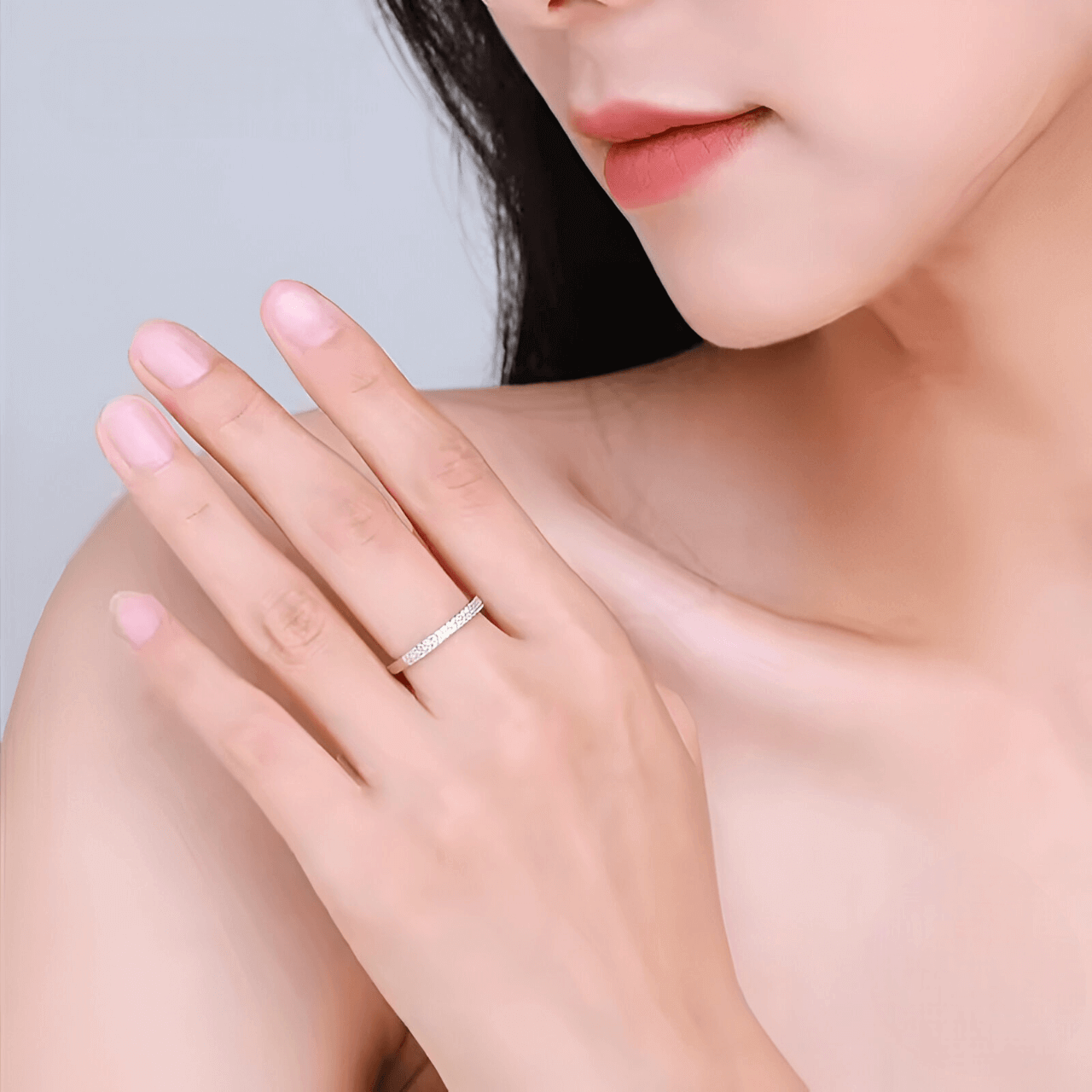 Alliance pavée en or blanc et rhodium sertie de diamants naturels portée au doigt d'une femme.