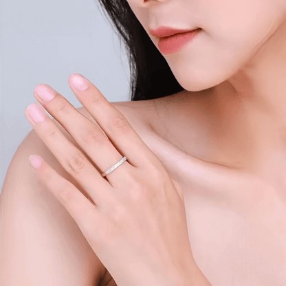 Alliance pavée en or blanc et rhodium sertie de diamants naturels portée au doigt d'une femme.