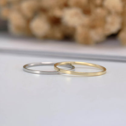 Alliances ruban épurées en or jaune et or blanc posées.