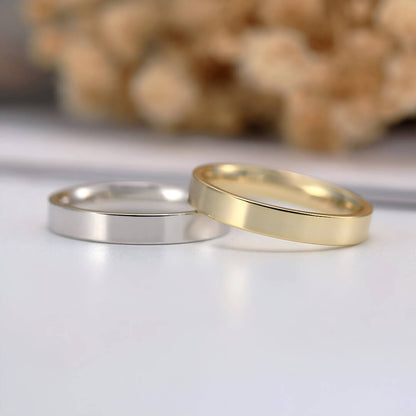 Alliances ruban épurées en or jaune et or blanc posées.