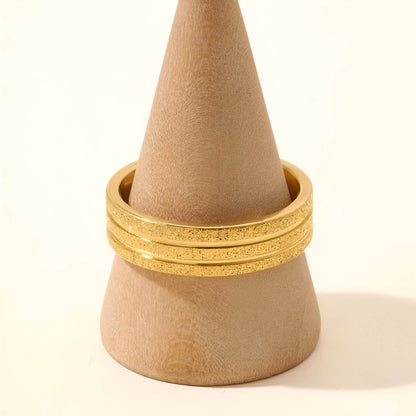 Alliance ruban en acier inoxydable et or jaune portée par un socle.