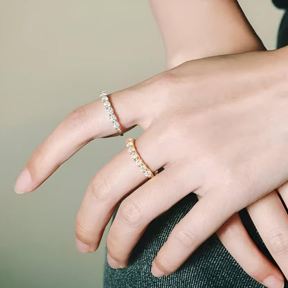 Alliances semi-éternité en or jaune et or blanc serties de diamants synthétiques portées aux doigts d'une femme.