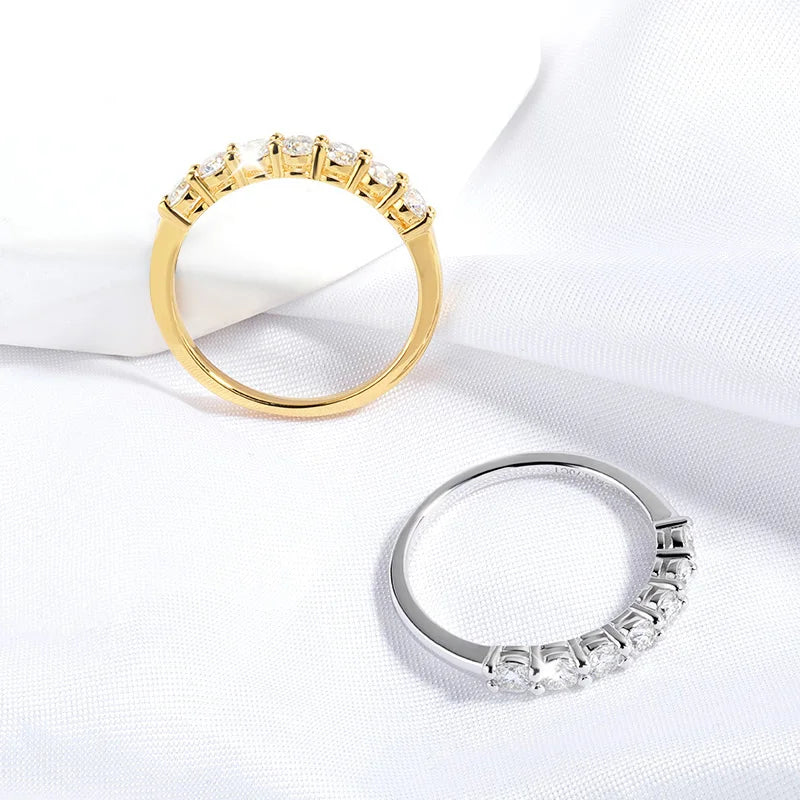 Alliances semi-éternité en or jaune et or blanc serties de diamants synthétiques sur une nappe blanche. 