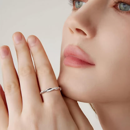 Alliance torsadée en or blanc et diamants synthétiques portée à l'index d'une femme.