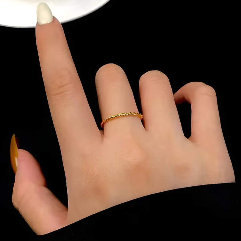 Alliance torsadée en or jaune portée au doigt d'une femme.