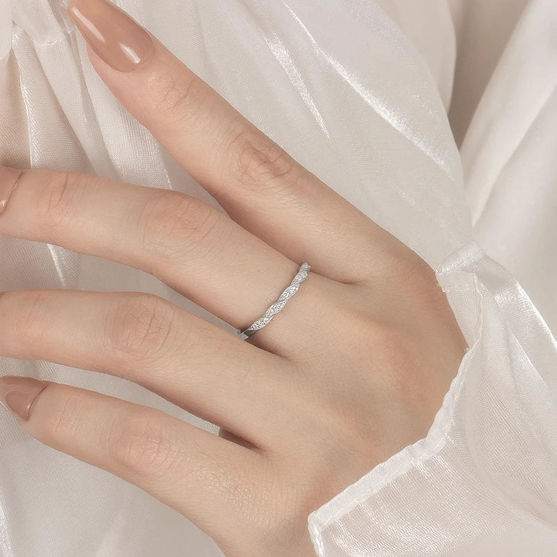 Alliance torsadée en or blanc et diamants synthétiques portée au doigt d'une femme.