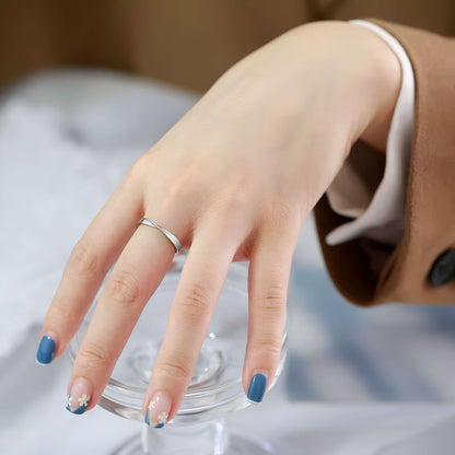 Alliance torsadée mobius en acier inoxydable et or blanc portée au doigt d'une femme vue de face.