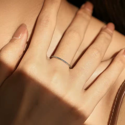 Alliance torsadée en argent 925 et rhodium portée au doigt d'une femme.