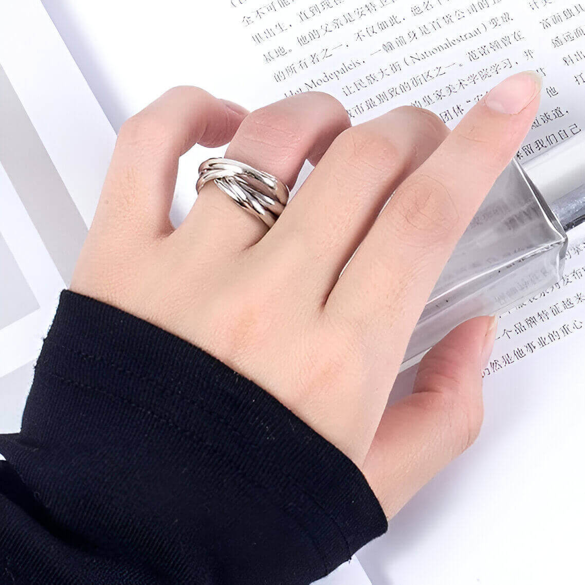 Alliance triple demi-jonc en acier plaqué or blanc portée au doigt d'une femme vue du dessus.