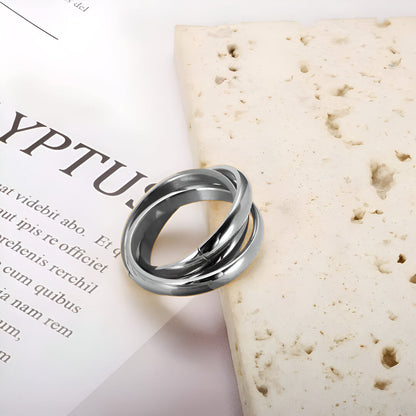 Alliance triple demi-jonc en acier plaqué or blanc posée sur une pierre blanche.