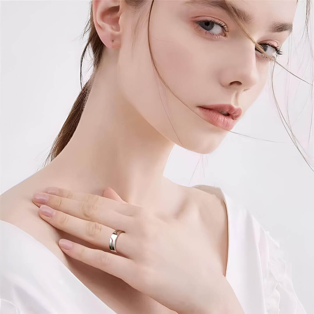 Anneau blanc rainuré fashion Éos en acier 316L porté au doigt d'une femme vue de loin.