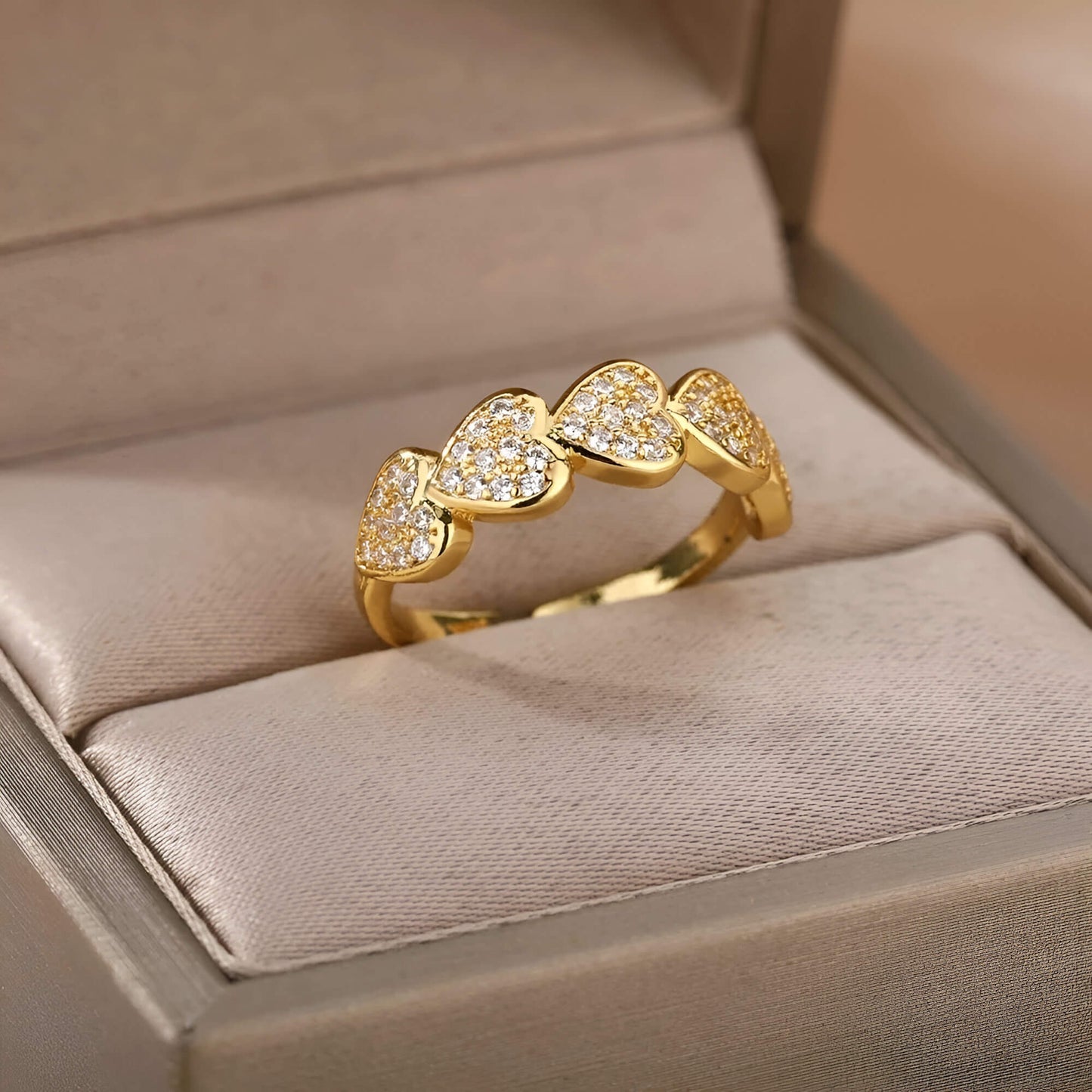 Bague ajustable cinq cœurs dorés sertis de petits diamants scintillants Hecate en acier 316L plaqué or jaune 18K rangée dans son écrin.