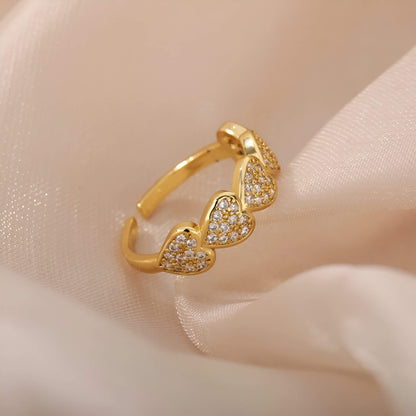 Bague ajustable cinq cœurs dorés sertis de petits diamants ronds Hecate en acier plaqué or jaune 18K posée.