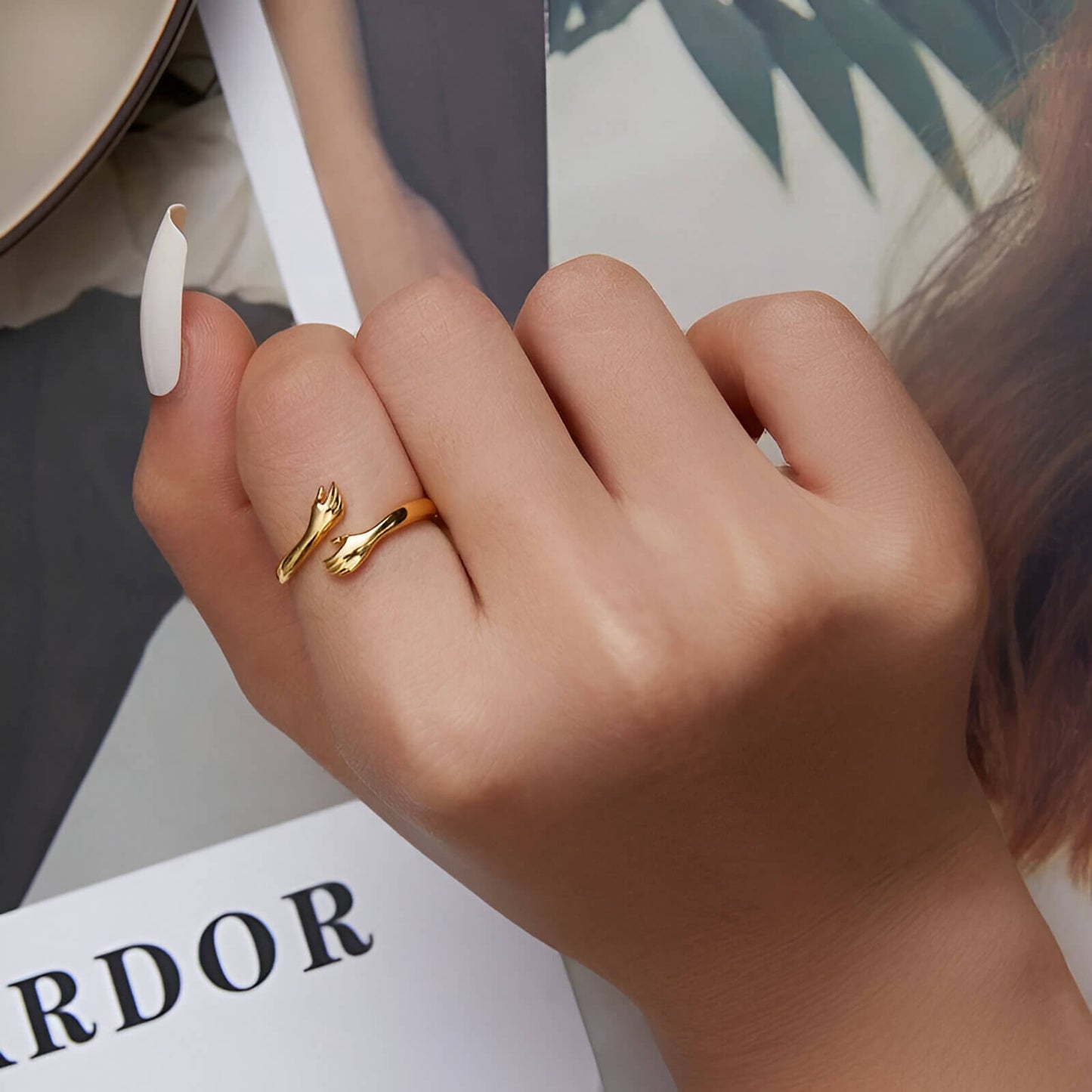 Bague ajustable main entrecroisée en argent 925 plaqué or jaune portée qu doigt d'une femme vue de proche.