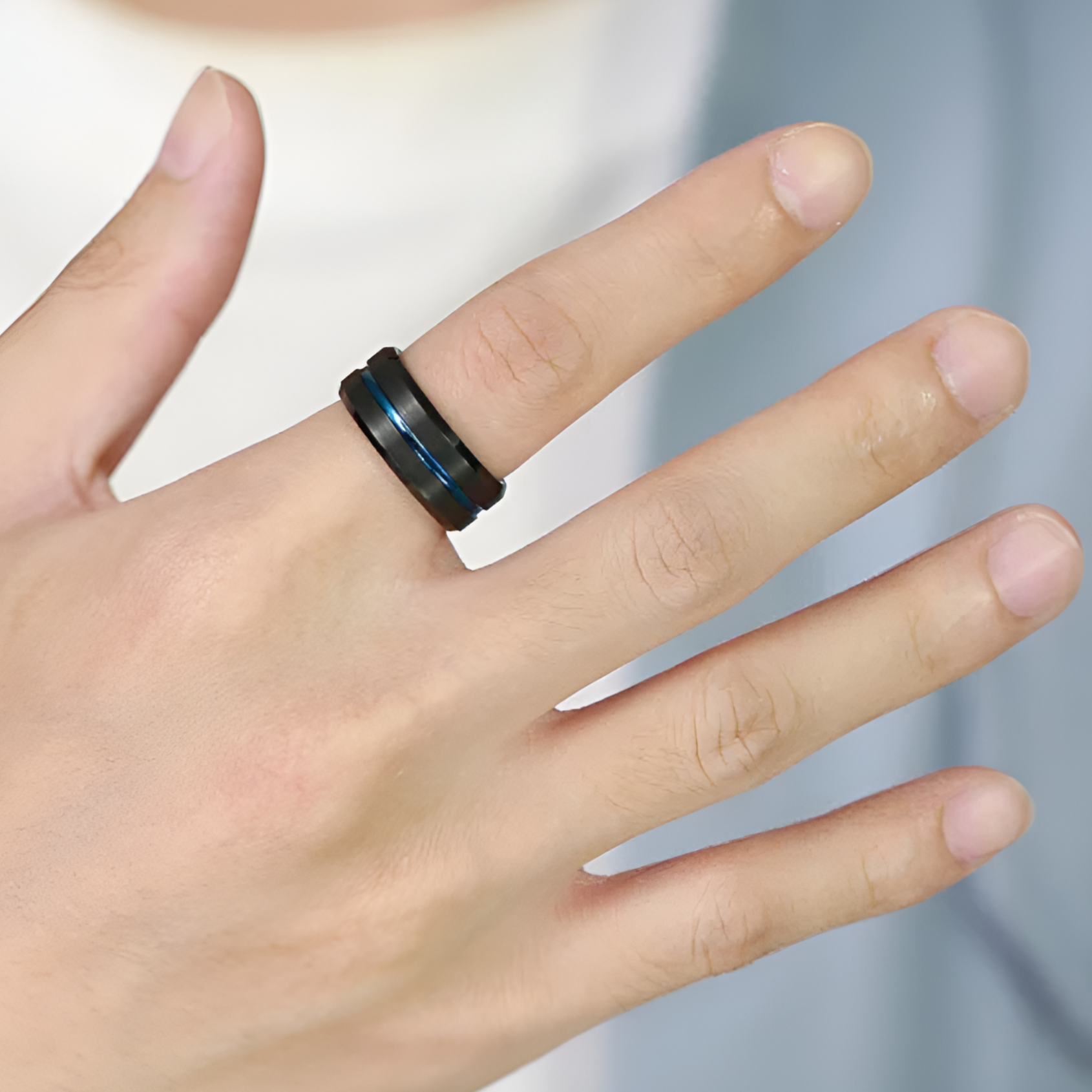 Bague bande bleue fashion homme Selwynen acier inoxydable 316L plaqué titane noir portée au doigt d'un homme vue de proche.