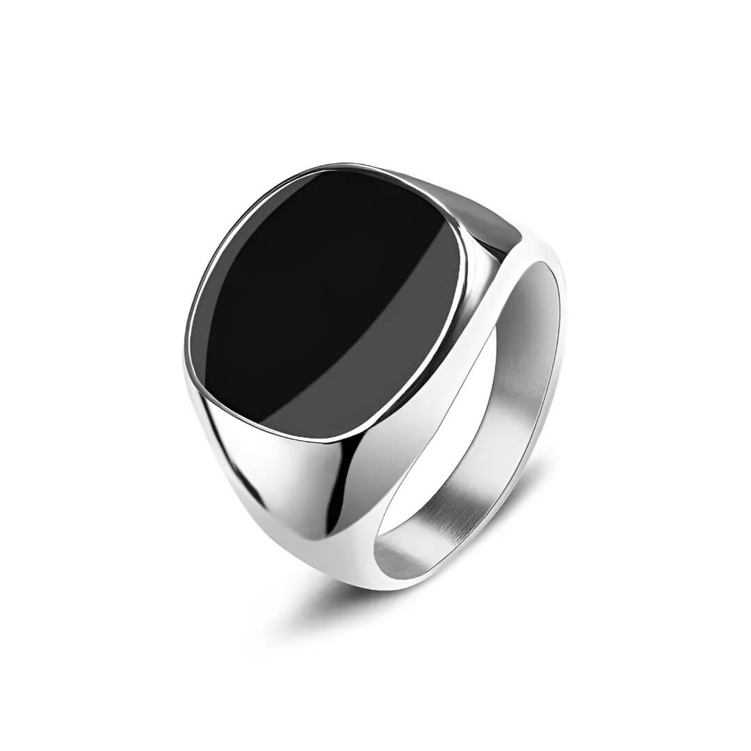 Bague chevalière en acier et or blanc sertie d'onyx sur fond blanc.