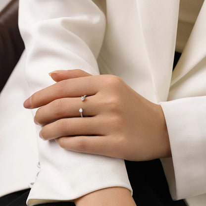 Bague d'engagement ouverte Clio en argent 925 rhodié et diamants portée au doigt d'une femme vue de face.
