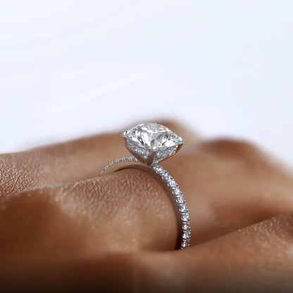Bague de fiançailles en argent rhodié orné d'un solitaire et de diamants portée au doigt d'une femme vue de proche.