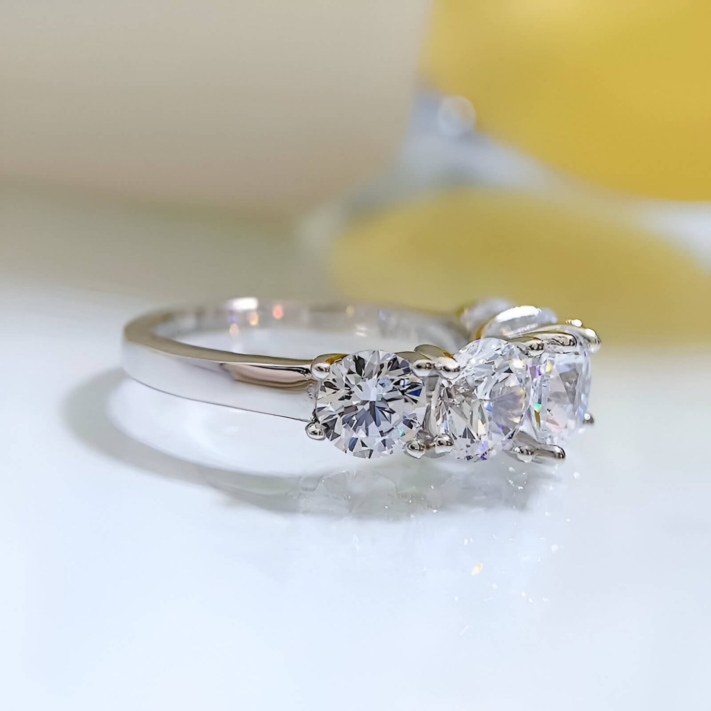 Bague de fiançailles cinq pierres en argent 925 plaqué or blanc et moissanites à plat vue de côté.